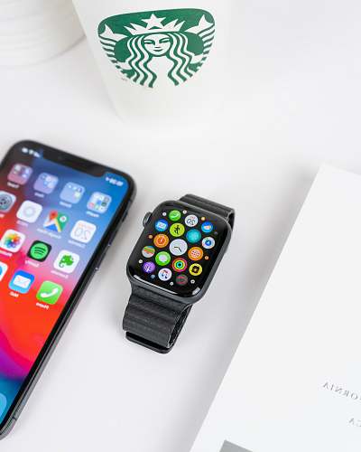cell phone black aluminum case Apple Watch with black Sport Band beside space gray iPhone X turned on mobile phone
